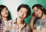 ジャングルポケット/集合(3人)/横型・バストアップ・衣装グレー・白・オレンジ・赤・青・チェック柄・斉藤右手上げ・首傾げ・センター太田口開け・背景緑/ナマーシャ