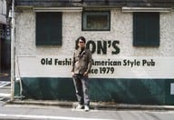 ライセンス/井本貴史/横型・全身・衣装カーキ・グレー・デニム・サングラス・両手ポケット・背景建物/公式生写真