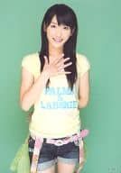 小原春香/膝上・衣装黄色・右手パー・左手後ろ・背景緑/公式生写真